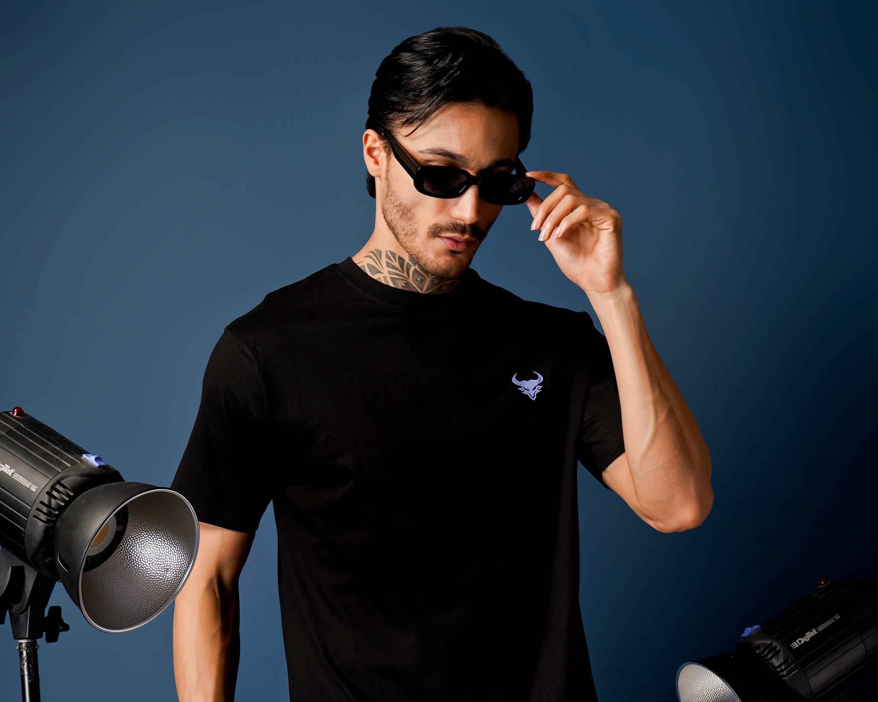 Durable Fashion: The Key to Sustainable Style - Model wearing sunglasses and a black t-shirt with stylish lighting.