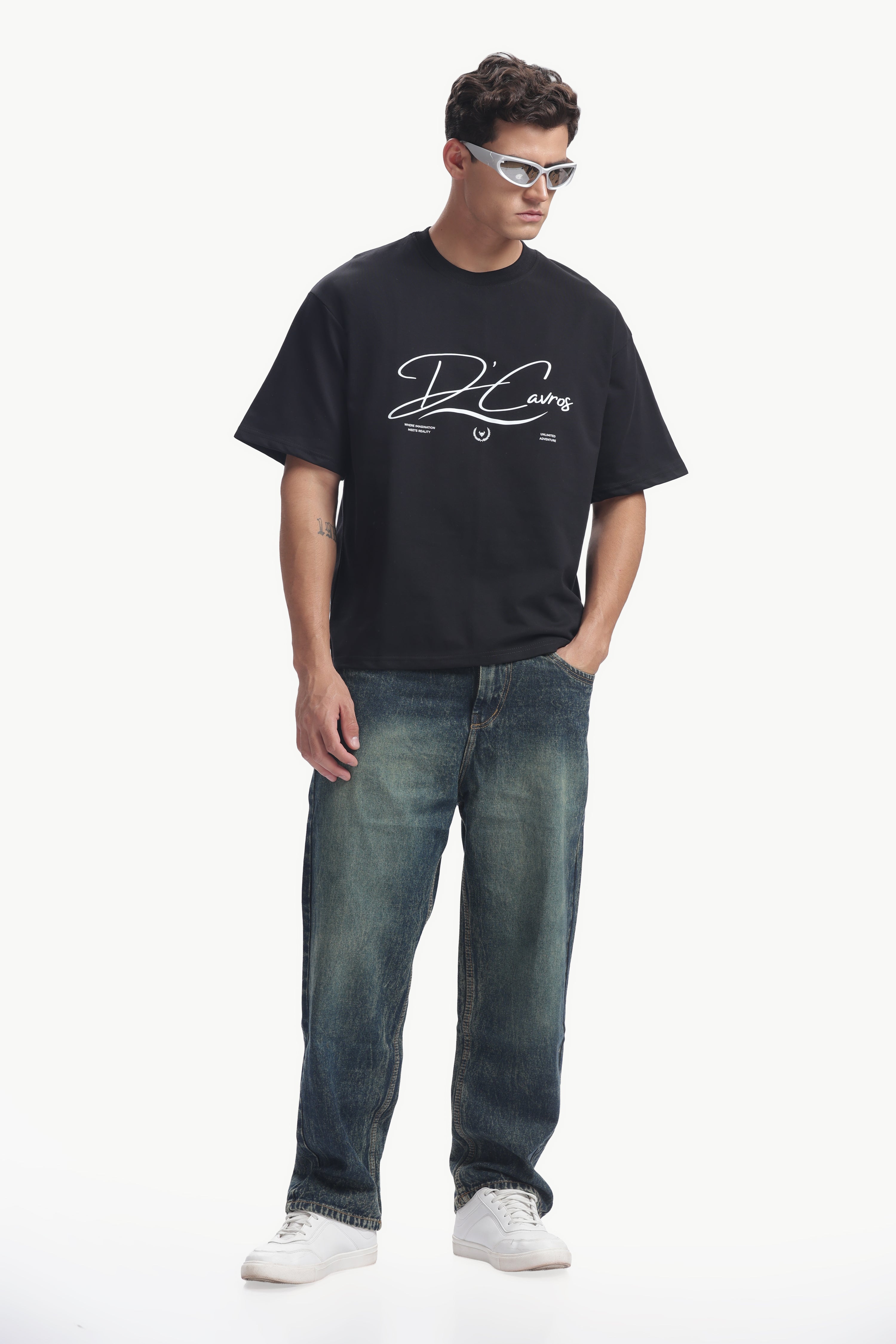 Model wearing Community Capsule Graphics Tee with bold typography and relaxed fit, paired with jeans and sunglasses.