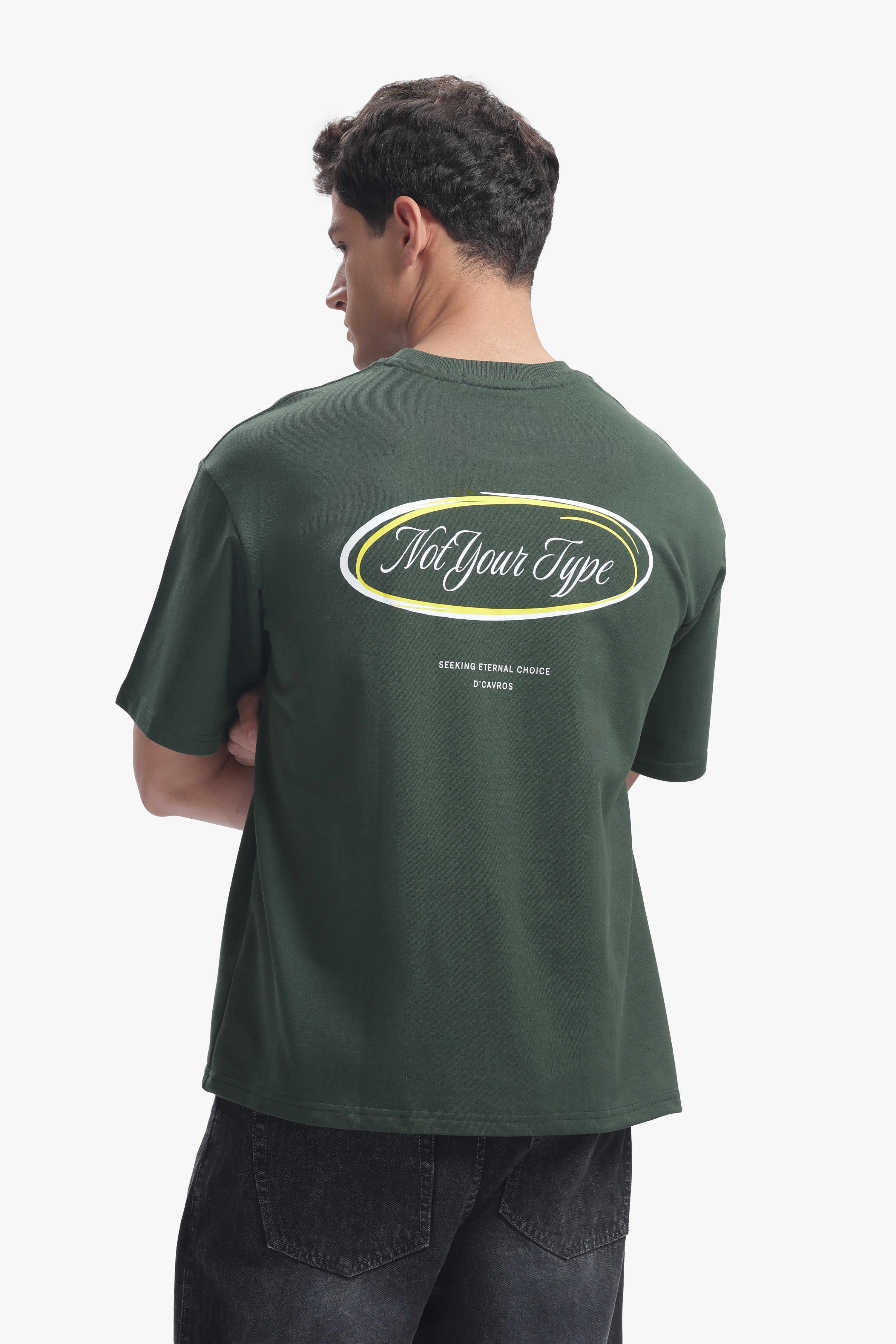 Back view of a model wearing the Not Your Type Oversized Fit Tee in dark green with a bold graphic design.