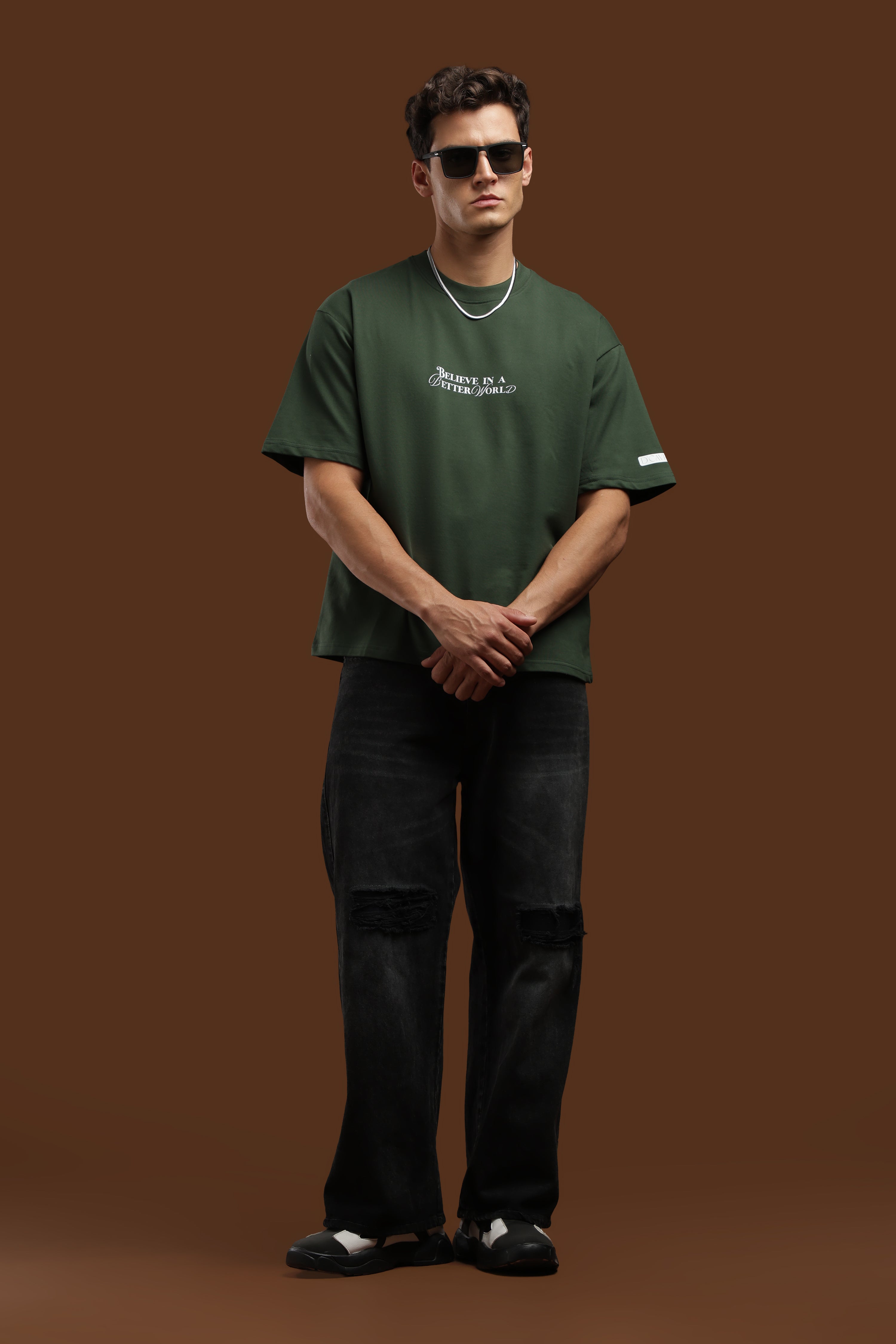 Model wearing Better World Printed Oversized T-Shirt in green with black jeans and sunglasses.