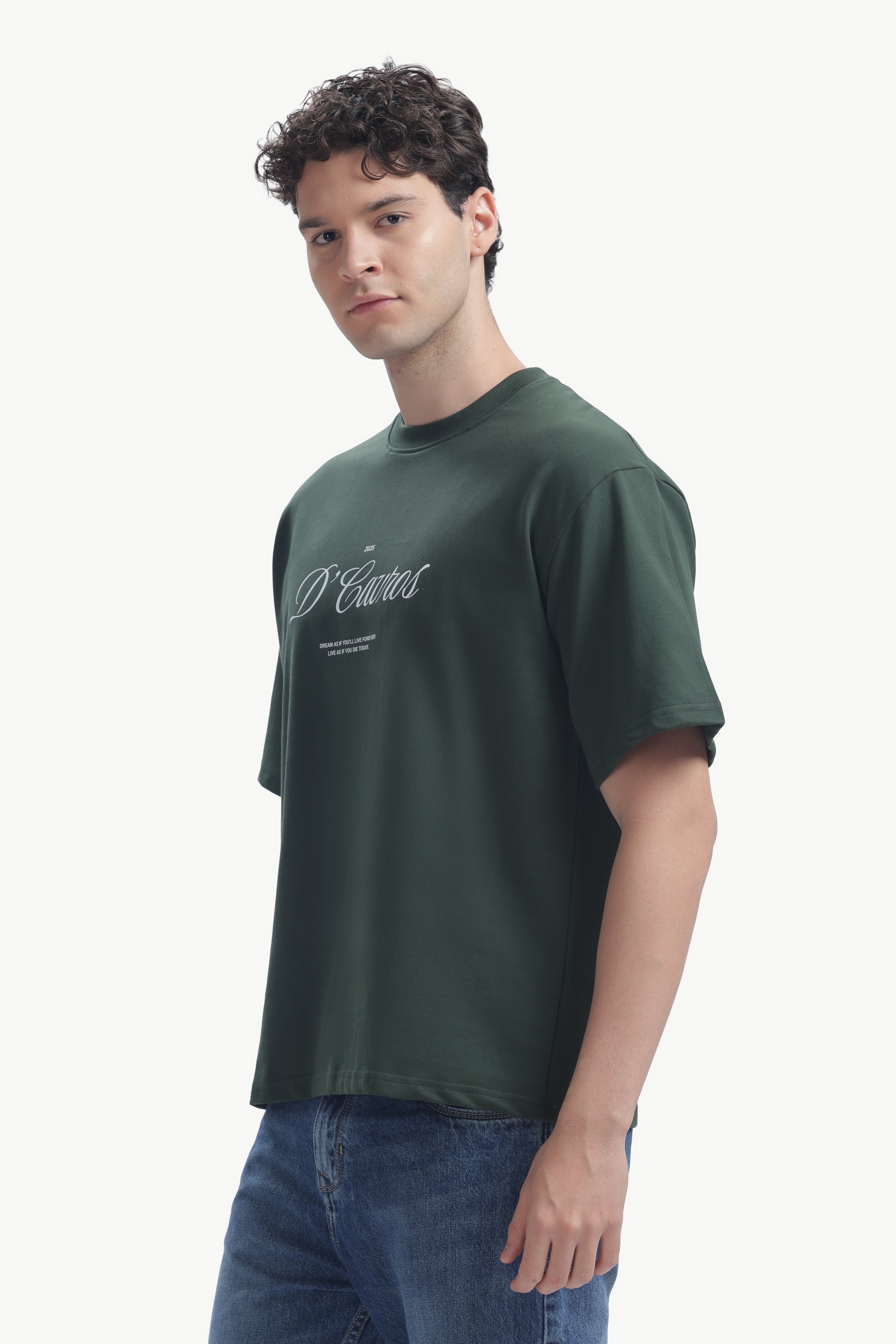 Model wearing a Classic Loose Fit Typography T-Shirt in dark green with D’Cavros script.