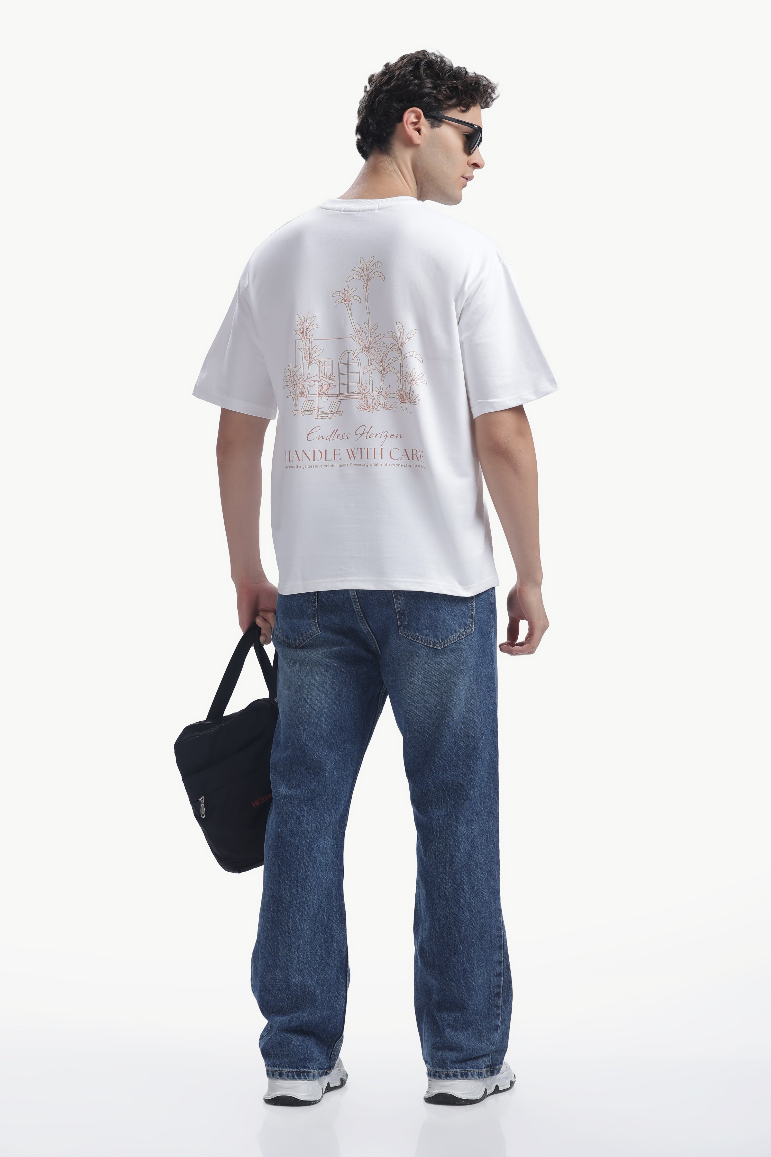 Model wearing Vintage Horizon Printed T-Shirt with palm artwork and relaxed fit, paired with blue jeans.