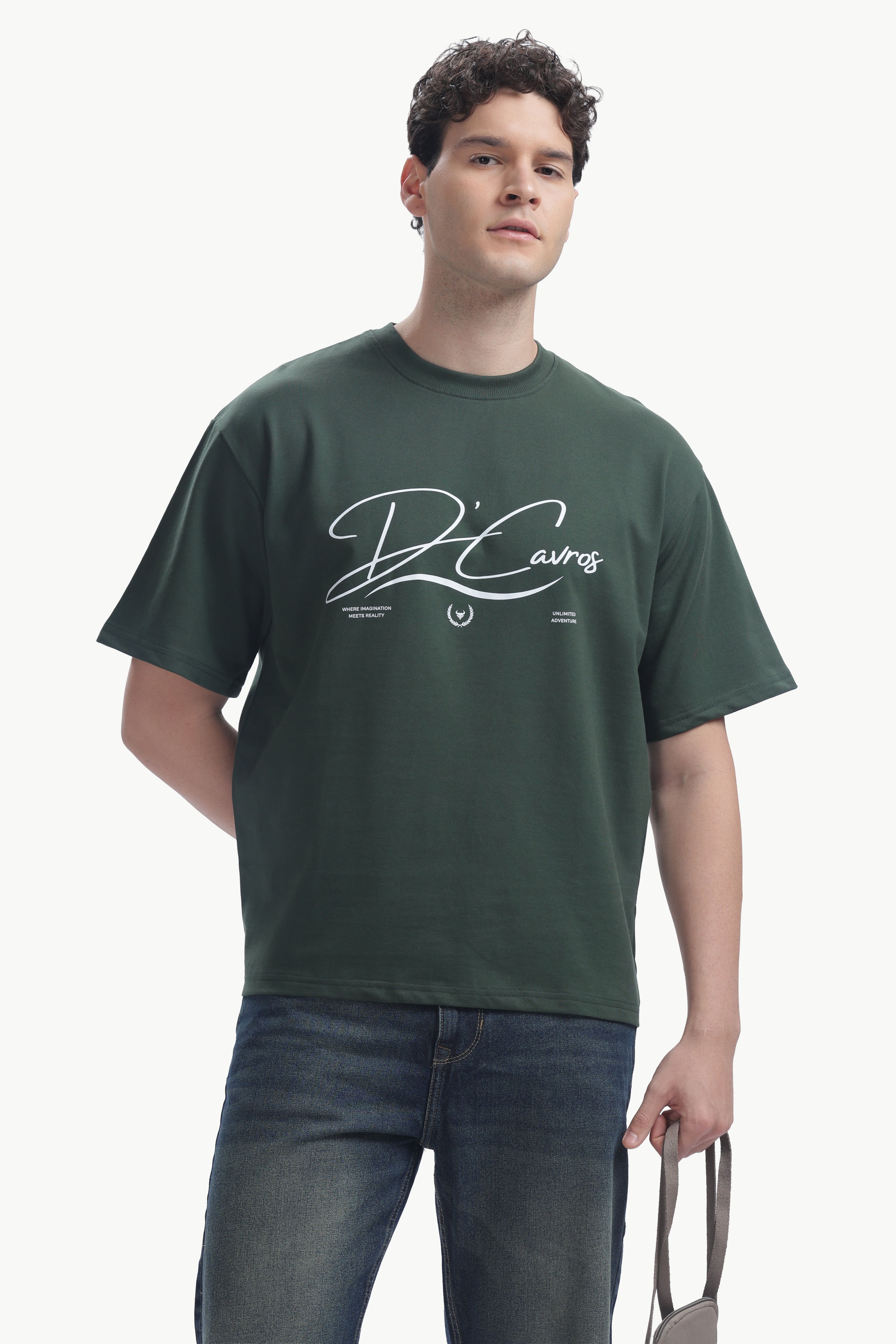 Model wearing the Community Capsule Graphics Tee in dark green with bold typography and relaxed fit.