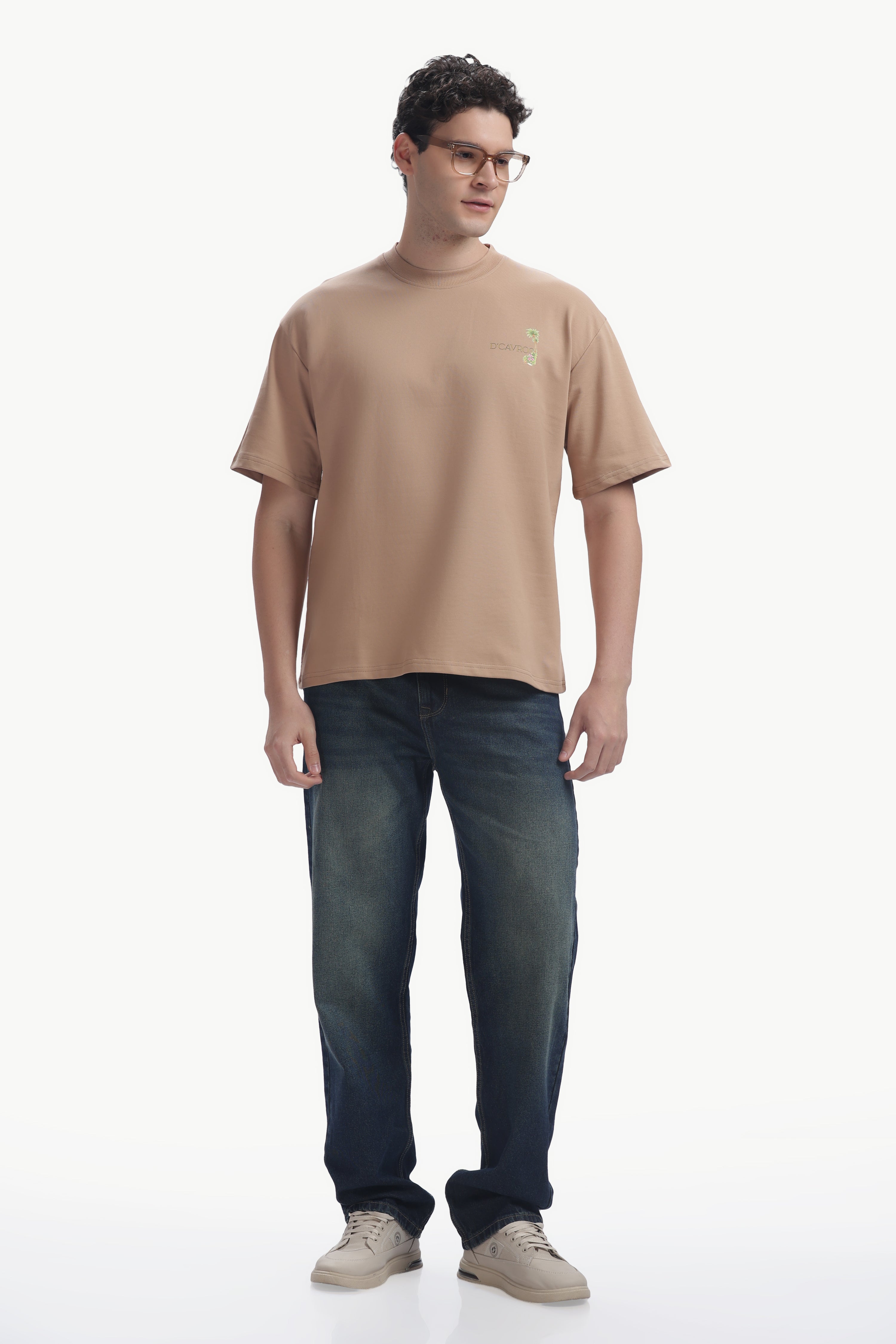 Man wearing Amalfi coast Oversized Fit T-Shirt in beige, paired with jeans and casual shoes, showcasing summer style.