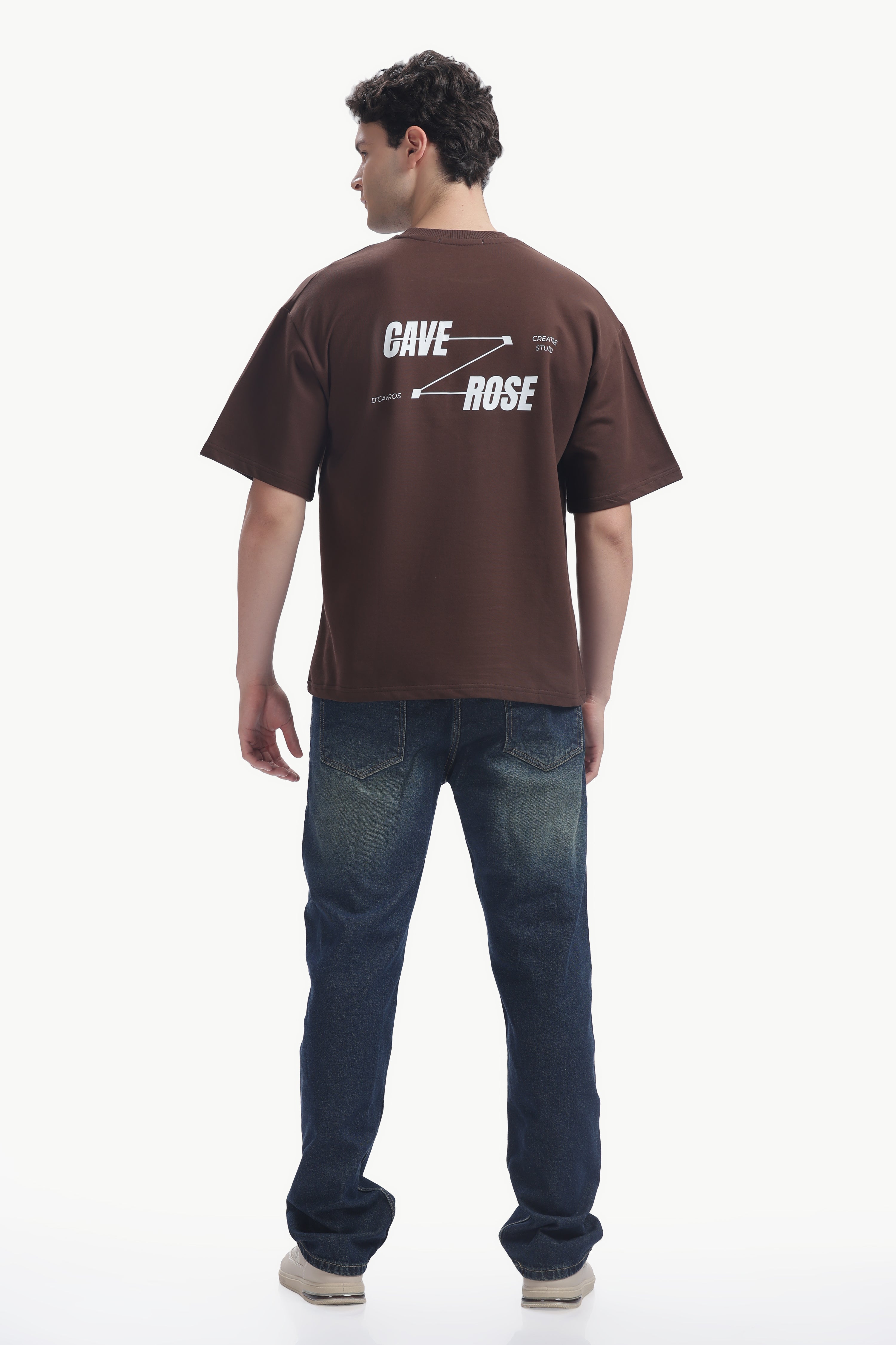 Back view of a man wearing a brown Cave-Rose Creative Studio Graphics Tee with bold typography.