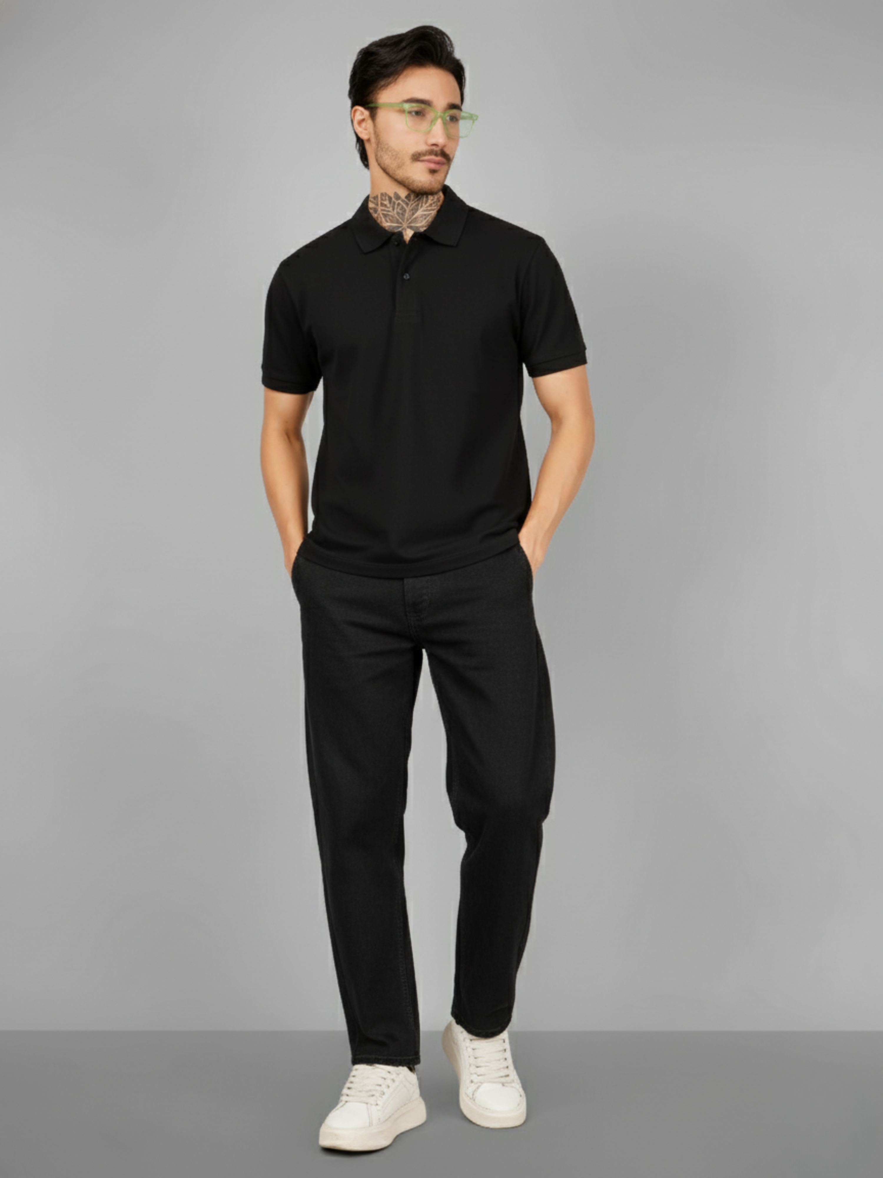 Man wearing a black polo shirt and pants with white sneakers on a gray background