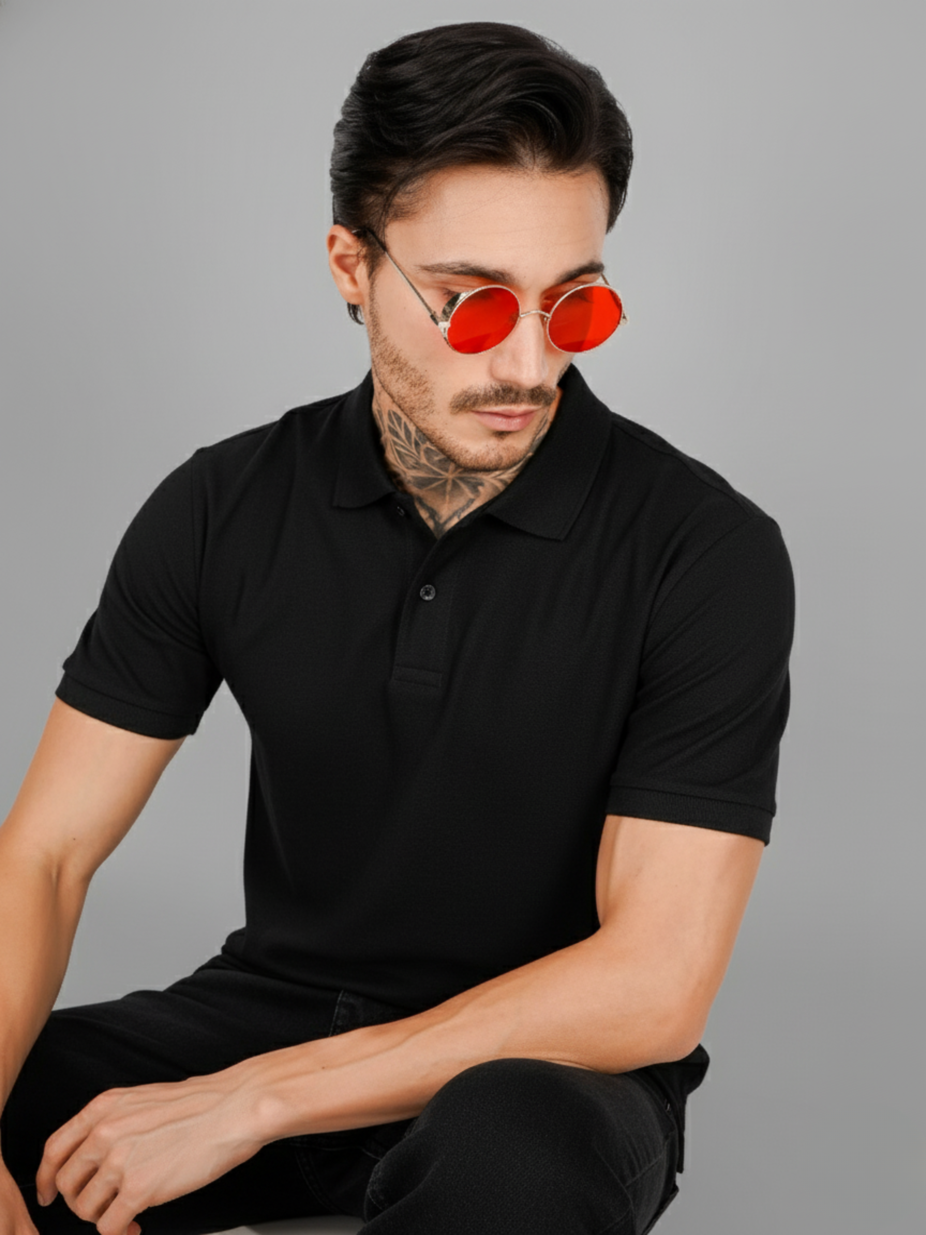 Man wearing a black polo shirt and red sunglasses against a gray background