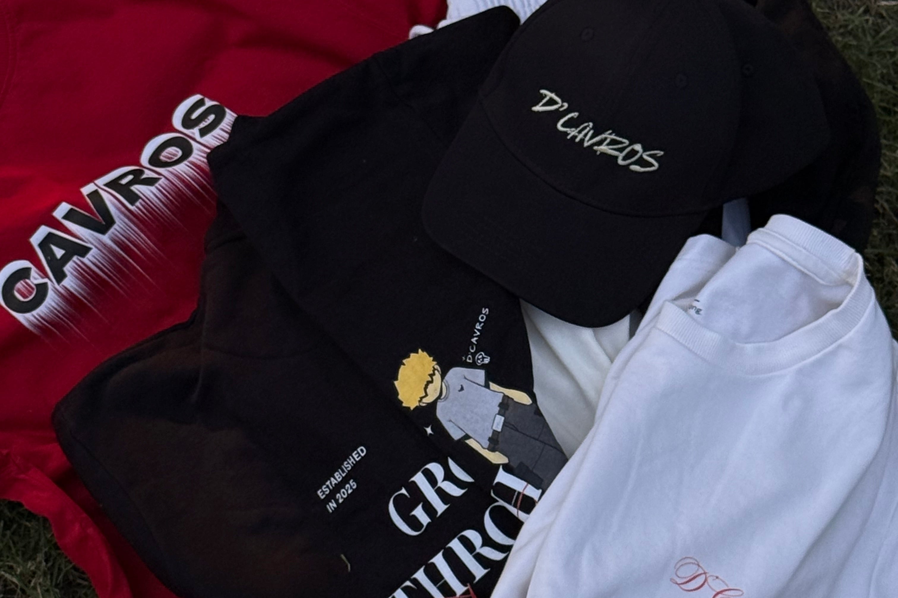 Clothing items including a black cap and white t-shirt on a grassy surface