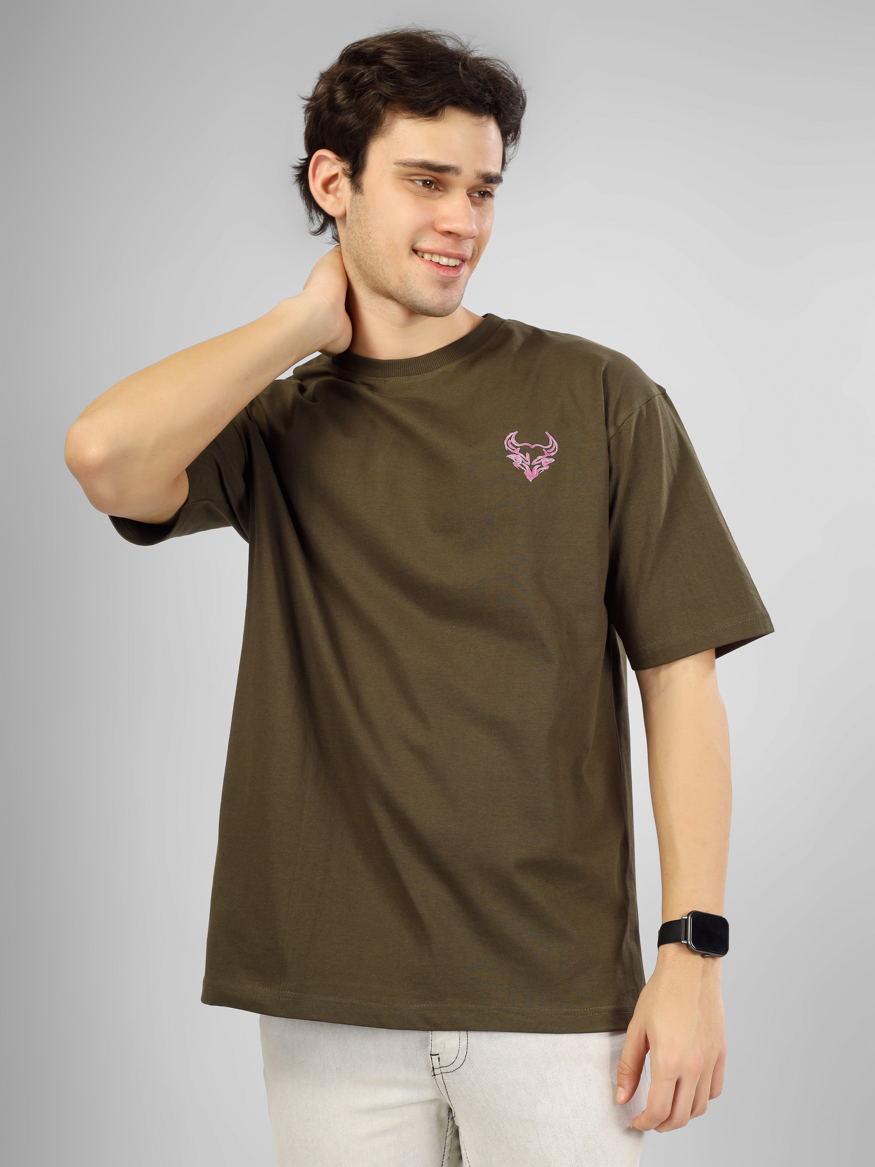 Man wearing olive green oversized D'Cavros T-shirt featuring a vibrant bull graphic and repeated D'Cavros logo text on the back, styled with beige jeans and sneakers.
