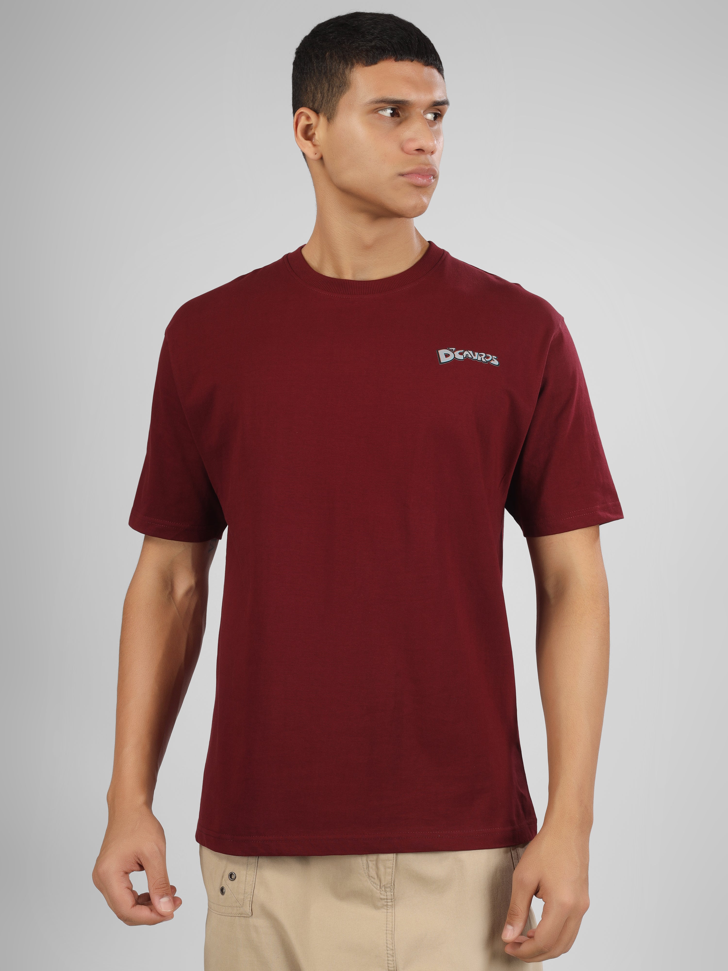 Male model wearing a maroon dcavros graphic T-shirt with a spiral text logo on the back and relaxed fit, styled with beige jeans.