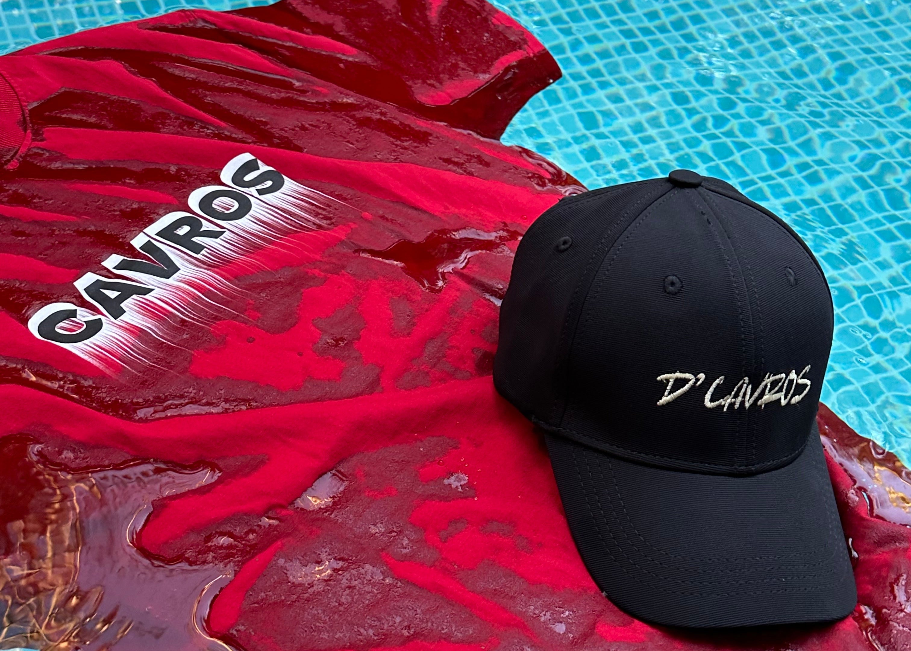 Black cap with 'Cavros' branding on a red garment by a pool.