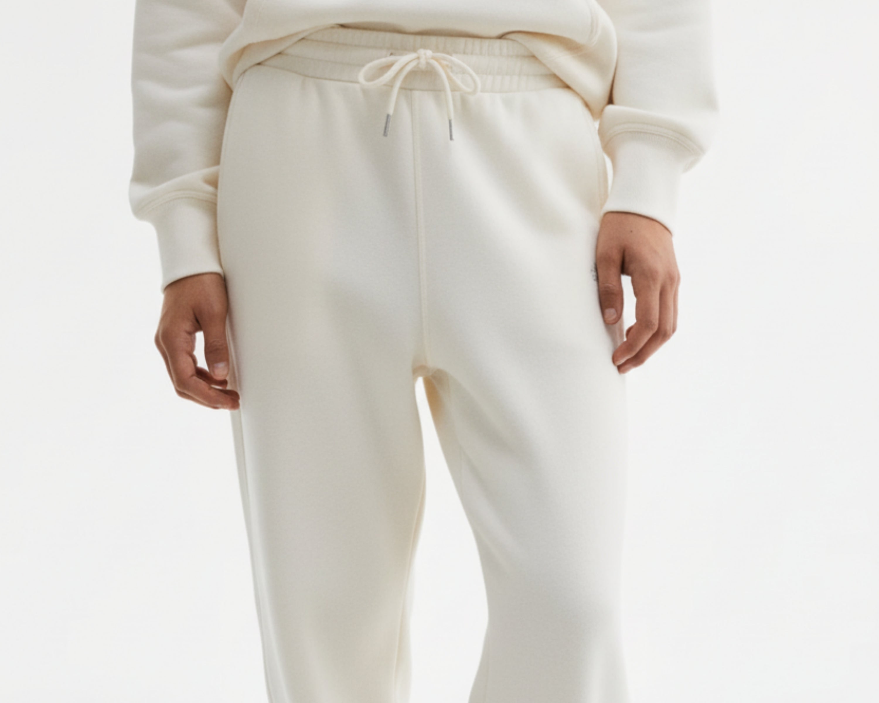 Person wearing white sweatpants and a matching top on a white background
