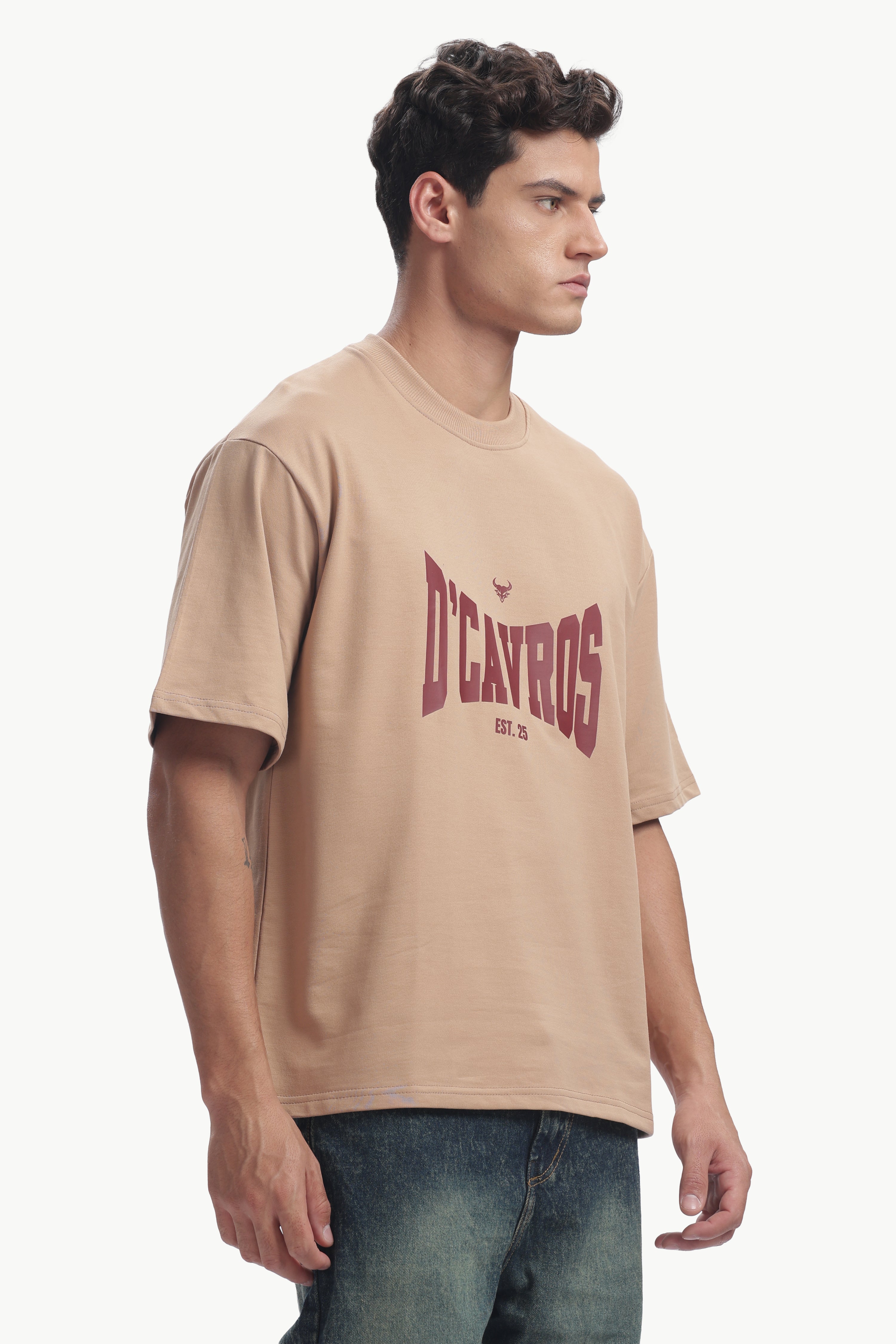 Man wearing Classic Typography Oversized Fit T-Shirt in beige with D'Cavros graphic design.