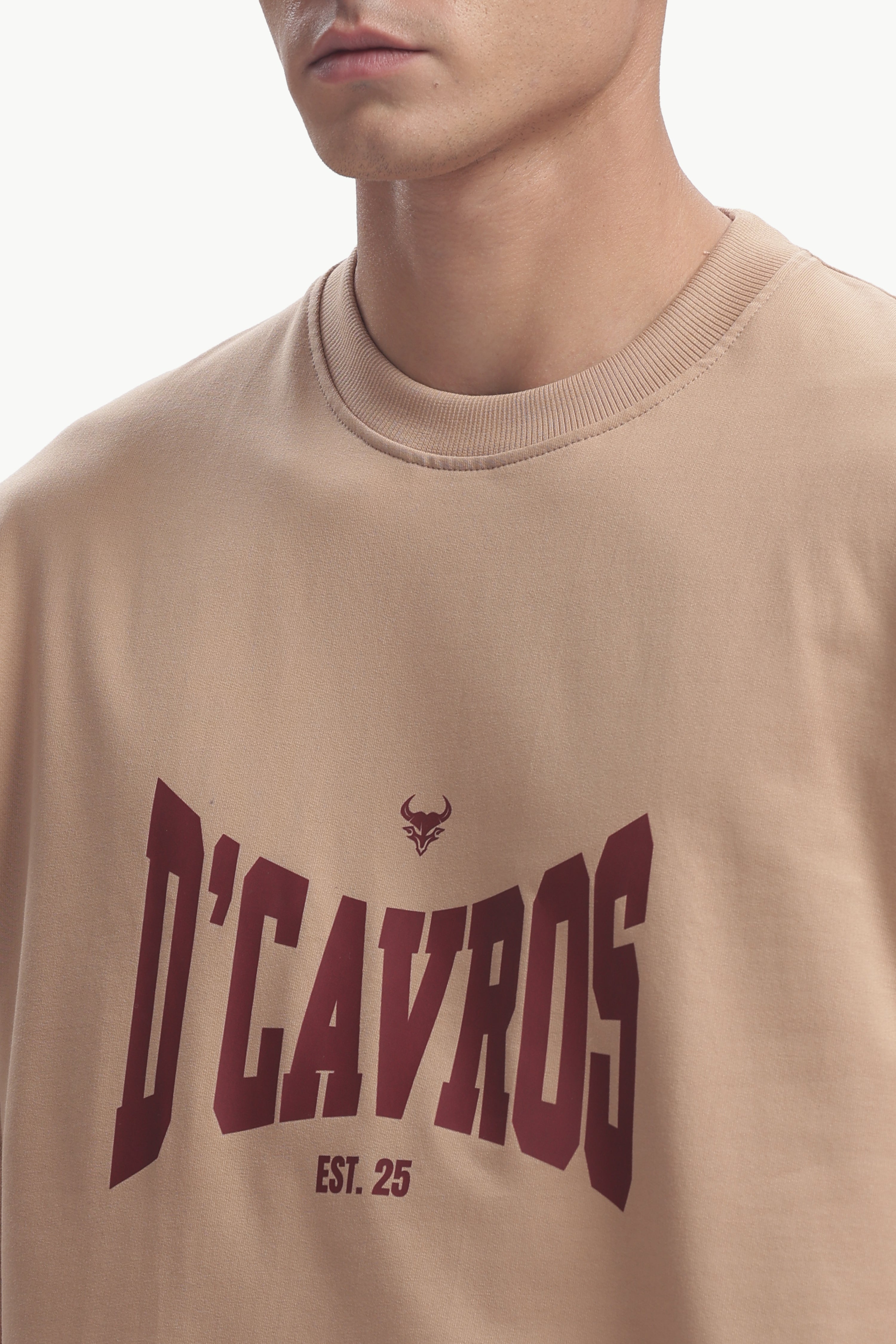 Close-up of model wearing Classic Typography Oversized Fit T-Shirt in beige with D’Cavros graphic design.