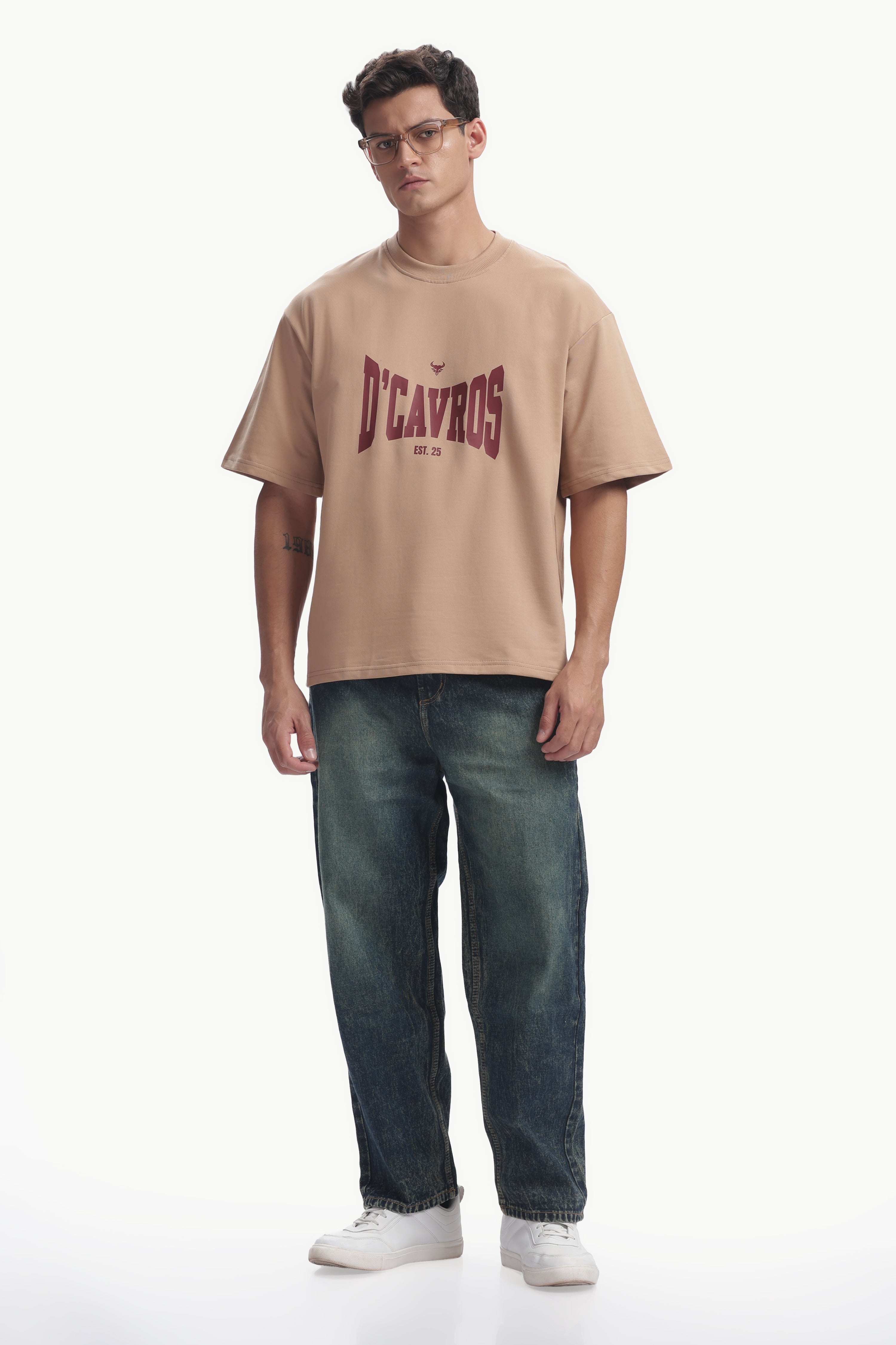 Model wearing Classic Typography Oversized Fit T-Shirt in beige with D'cavros graphic, styled for casual everyday wear.