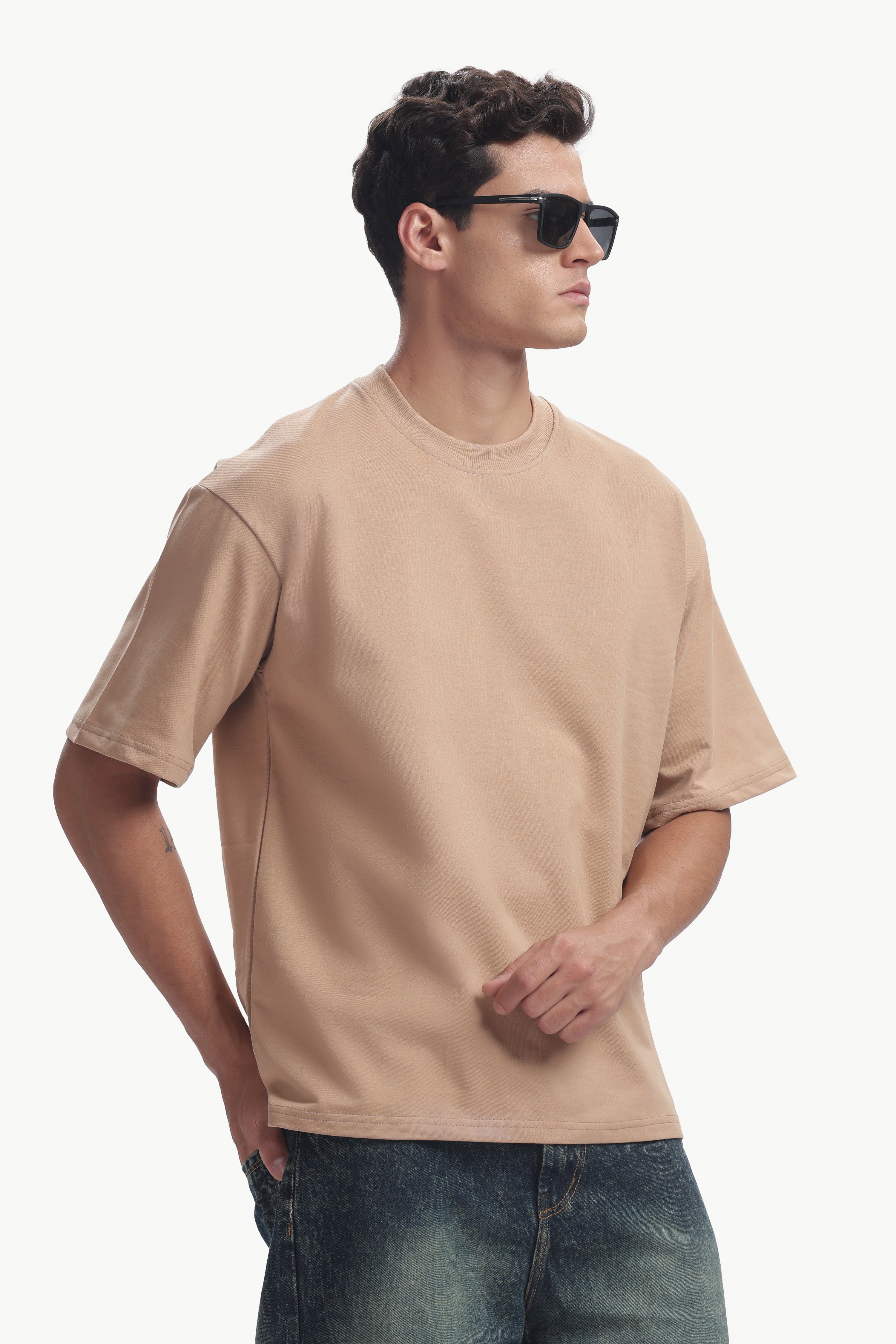 Model wearing Oversized Fit Focal Point T-Shirt in beige, showcasing relaxed fit and stylish sunglasses.