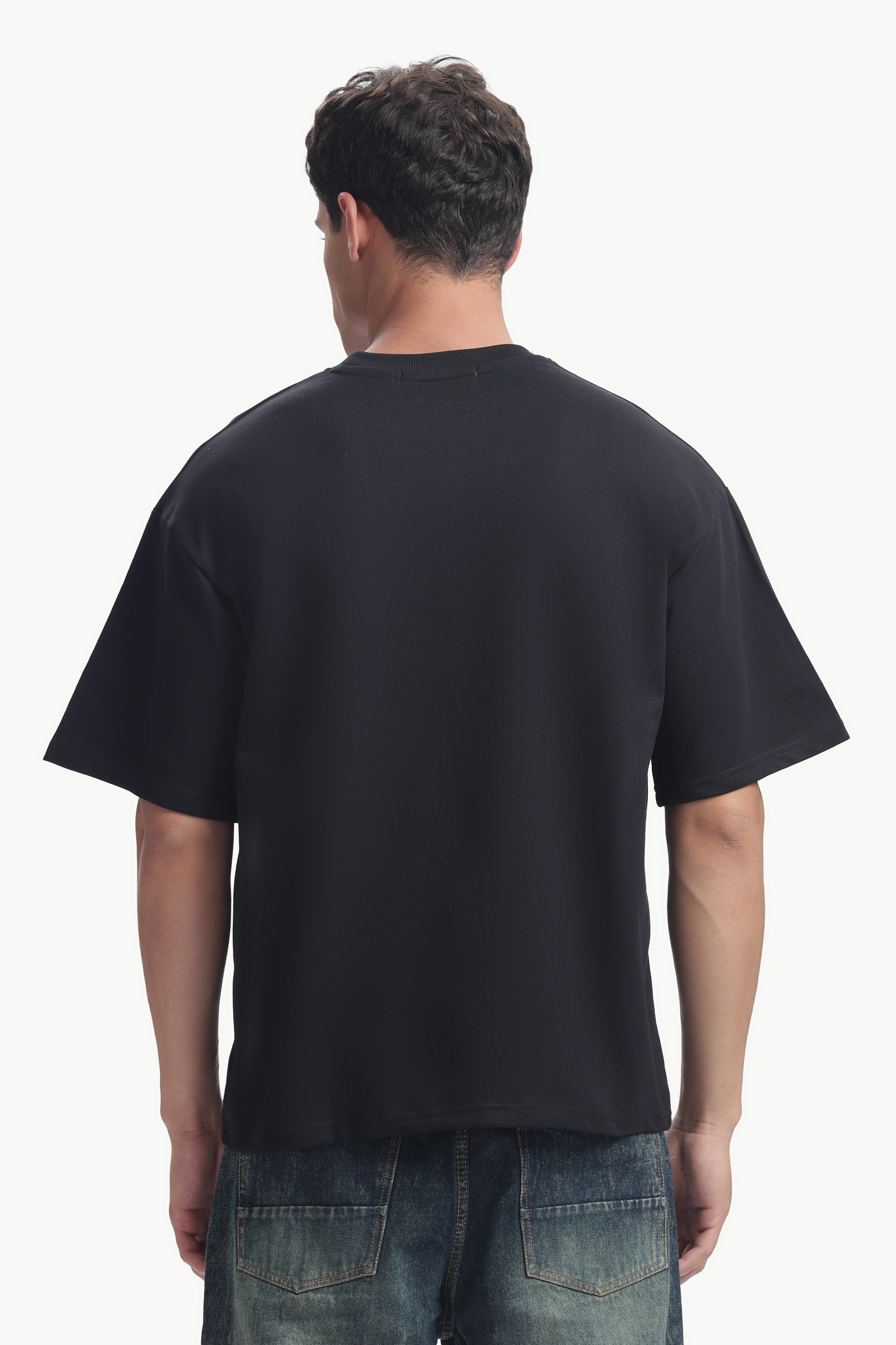 Back view of a man wearing a black Community Capsule Graphics Tee with a relaxed fit.