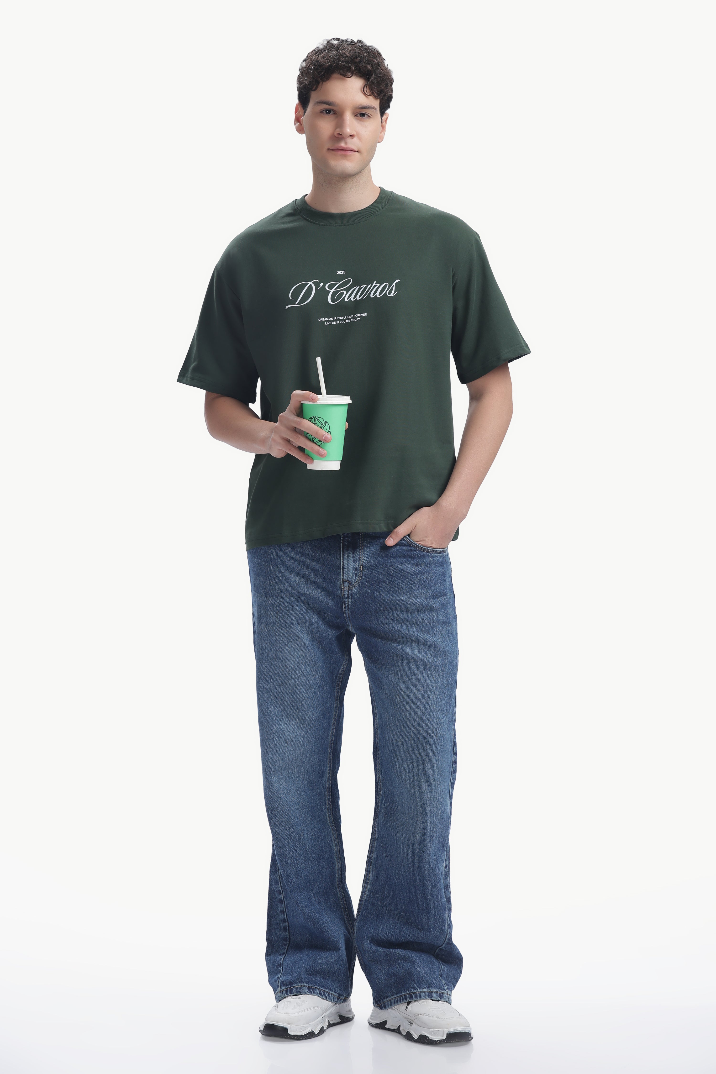 Model wearing Classic Loose Fit Typography T-Shirt with D’Cavros script, paired with jeans and holding a drink.