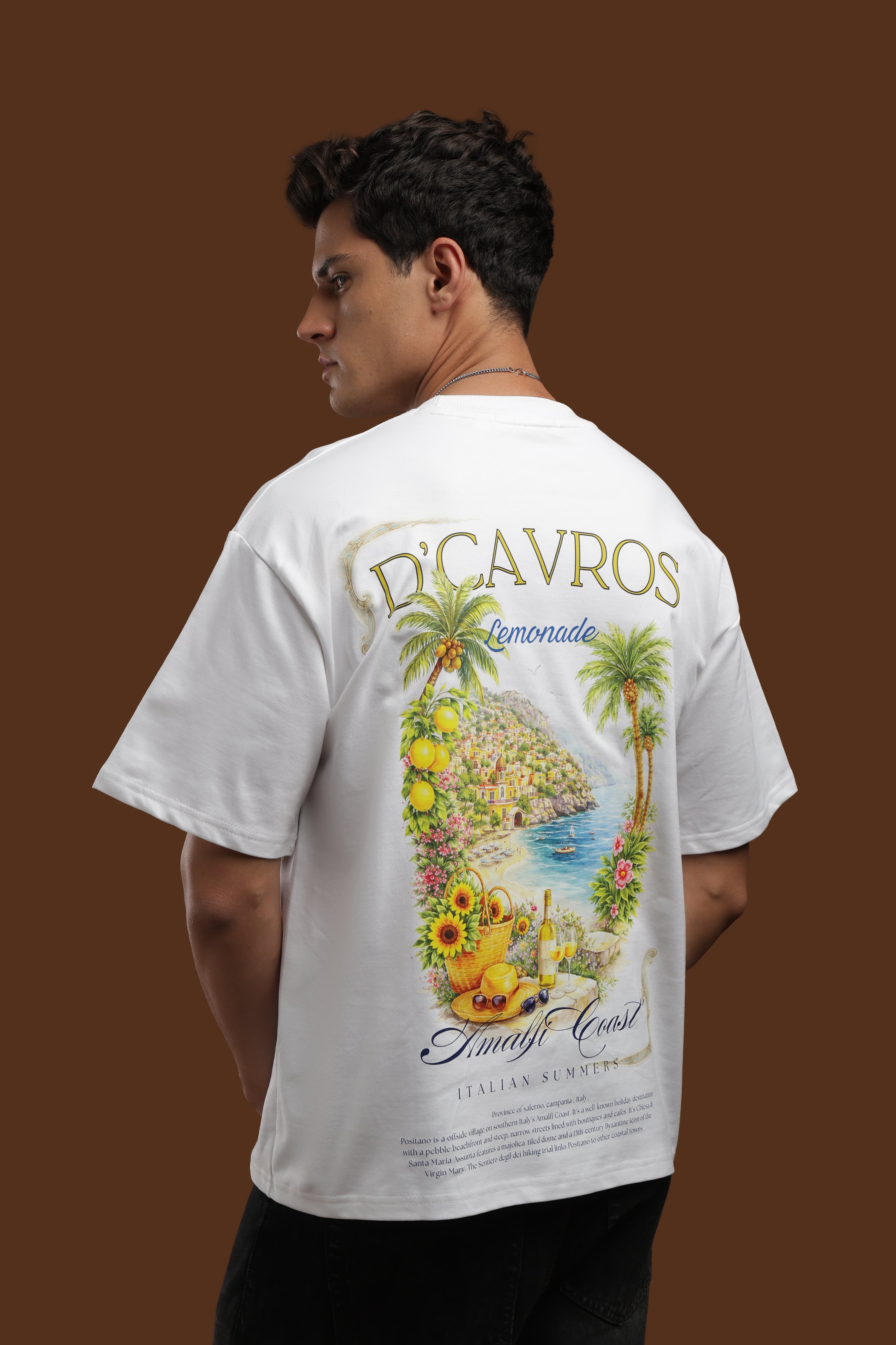 Model wearing an Amalfi coast Oversized Fit T-Shirt with a colorful coastal back print.