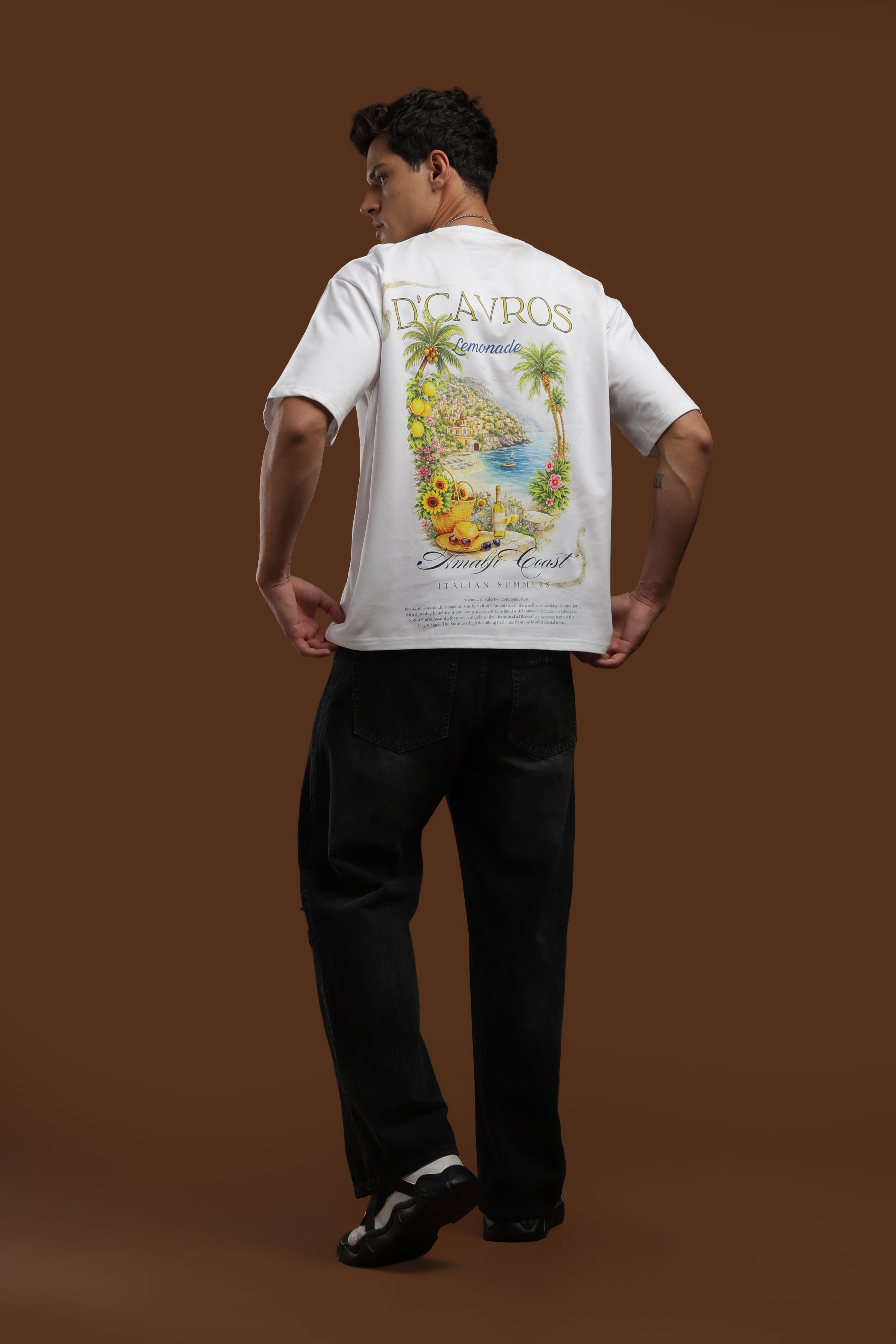 Model wearing an Amalfi coast Oversized Fit T-Shirt with vibrant coastal print on the back, perfect for summer style.